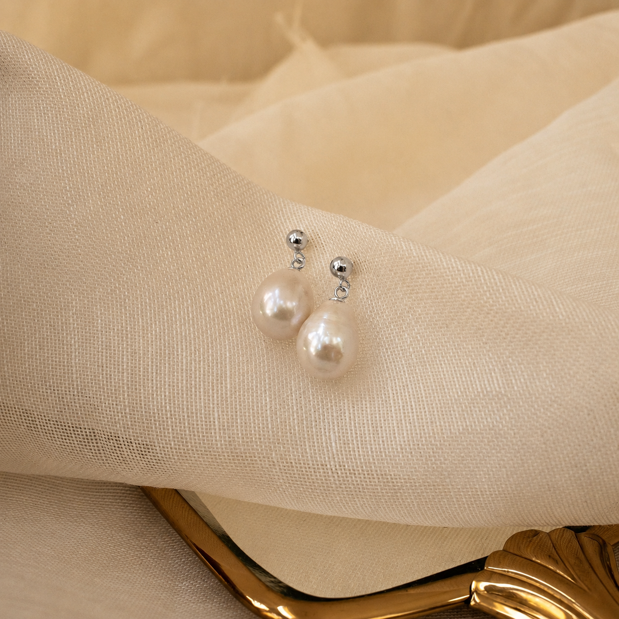 Pearl earrings on a beige fabric background
